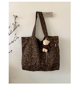 Detail of leopard print canvas tote bag featuring a cute plush bear charm accessory