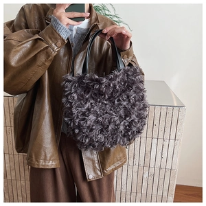 Dettaglio della texture in finta pelliccia riccia di una borsa a secchiello con manici