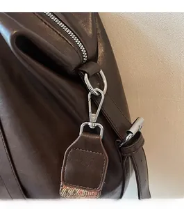 Détail de la quincaillerie argentée brillante et du cuir marron foncé du grand sac cabas