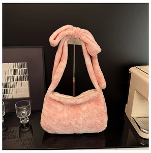 Detail of light pink plush shoulder bag featuring a large decorative knotted bow strap