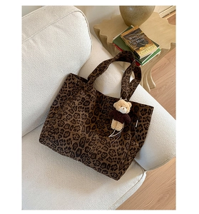 Detail of leopard print canvas tote bag featuring a cute teddy bear charm on fabric