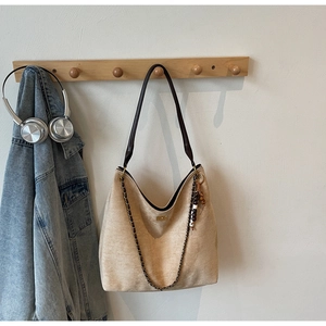 Detail of beige suede hobo bag with deep brown leather strap and woven metallic chain