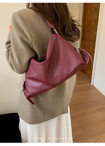Detail view of burgundy pebble leather shoulder bag with adjustable silver buckle strap