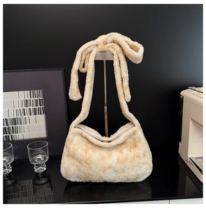 Detail of plush shoulder bag featuring tied bow strap and soft cream faux fur texture