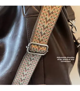 Détail de la bandoulière tissée réglable avec boucle argentée sur sac en cuir brun