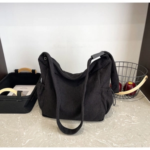 Detail of black corduroy hobo bag showing ribbed texture and wide adjustable strap