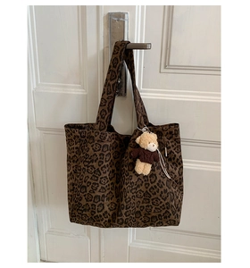 Detailed shot of leopard print canvas tote bag with a cute bear plush charm on a handle