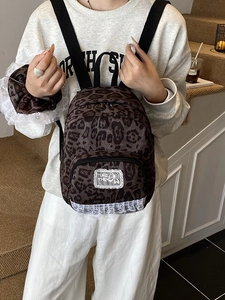 Vintage leopard print backpack with white lace trim and bow patch shown on a model