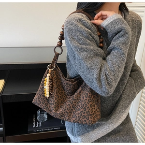 Detail der Leopard-Tasche mit Griffen aus Holzperlen und dekorativen Anhängern