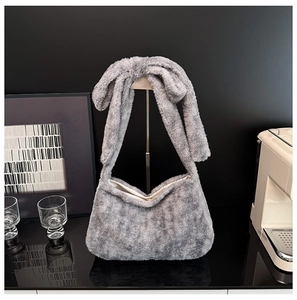 Close-up of plush grey faux fur shoulder bag featuring a large decorative bow detail