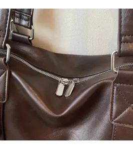 Détail des fermetures éclair argentées et coutures sur le sac à main en cuir marron