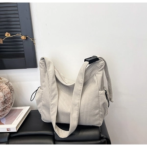Detail of beige corduroy tote bag featuring adjustable wide strap and side drawstring pocket