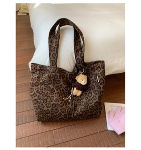 Detail of leopard print canvas tote bag featuring a cute teddy bear plush charm