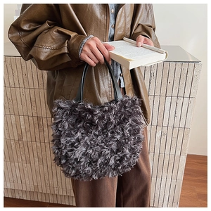 Detail of grey curly faux fur bucket bag with black leather handle in autumn street style