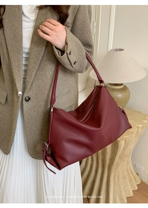 Detail view of large burgundy pebble leather shoulder bag with adjustable strap and silver zip