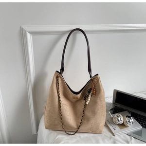 Detail of khaki suede hobo bag featuring dark woven chain and beaded pendant accents