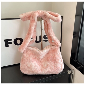 Détail du sac à main rose en peluche avec un grand nœud sur la bandoulière en polaire