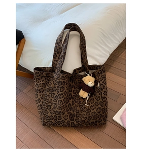 Close-up of leopard print canvas tote bag with dark brown pattern and cute bear charm