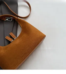 Gros plan du sac sous le bras en daim marron avec fermeture éclair en argent et texture