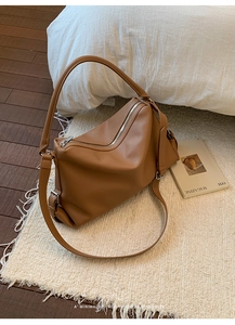 Detailed view of caramel brown lychee leather shoulder bag on a soft carpet