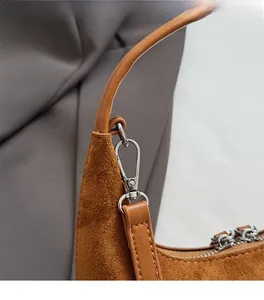 Détail du crochet argenté et de la texture en daim marron sur le sac à bandoulière