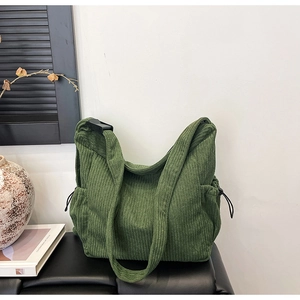 Detail of dark green corduroy tote bag featuring adjustable strap and drawstring side pocket