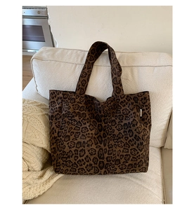 Detail of leopard print canvas tote bag featuring thick texture and branded side label