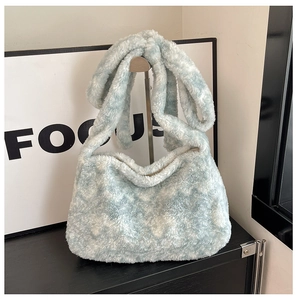 Détail d'un sac à bandoulière en peluche bleu clair et blanc sur un support métallique