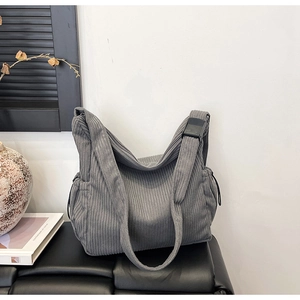 Detailed texture of grey corduroy tote bag showing wide strap and adjustable buckle