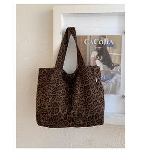 Detail of leopard print canvas tote bag hanging on a vintage textured wall