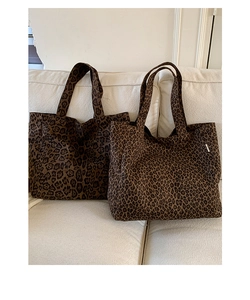 Detail shot of two leopard print canvas tote bags with different pattern densities on a sofa