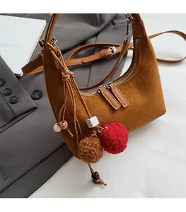 Détail du sac hobo en daim marron avec pompons colorés et breloques en perles de bois
