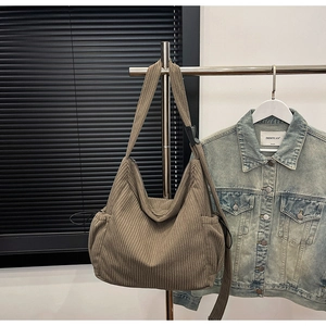 Detail view of corduroy shoulder bag showing vertical rib texture and drawstring side pocket