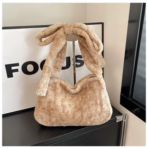 Détail du sac hobo en peluche beige avec un grand nœud décoratif sur la bandoulière