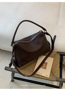 Detail of retro dark brown lychee pattern leather shoulder bag on a rattan bench