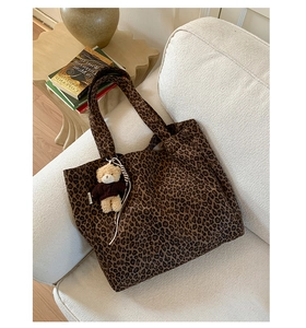 Detailed shot of leopard print canvas tote bag with a small bear pendant on a sofa
