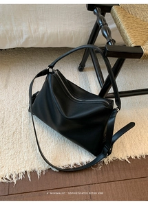 Detail of minimalist black lychee grain leather tote with silver zipper and dual straps