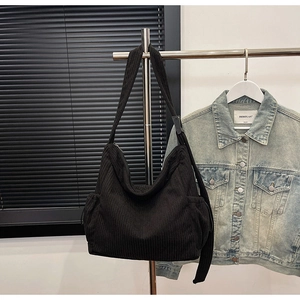 Detail of black corduroy shoulder bag with side drawstring pockets and zip closure
