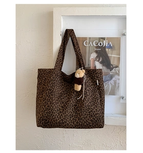 Detailed close-up of leopard print canvas tote bag with a cute brown plush bear charm
