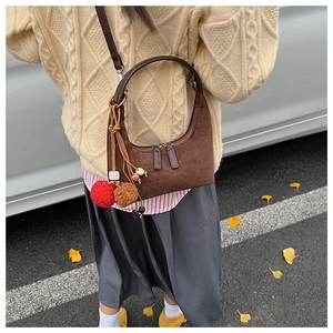 Détail du sac hobo mat marron foncé avec pompons en peluche et breloque en perles