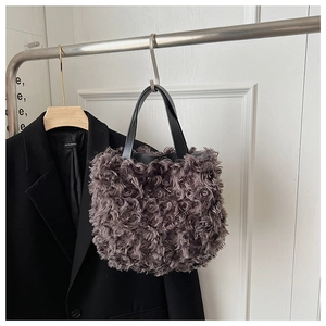 Dettaglio ravvicinato della borsa a secchiello in finta pelliccia grigio scuro con manici