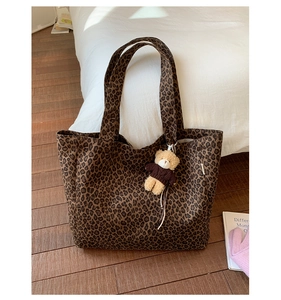 Detail of leopard print canvas tote bag featuring a cute brown plush bear charm