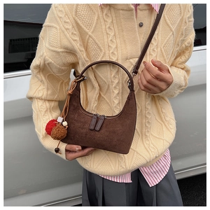 Détail d'un sac hobo en daim marron avec double fermeture éclair et pendentif à perles coloré