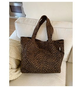 Close-up of leopard print canvas tote bag with side label on a soft fabric sofa