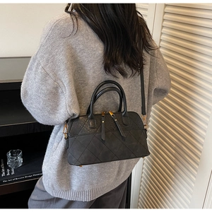 Detail of black quilted shell bag with frosted texture and elegant double handles