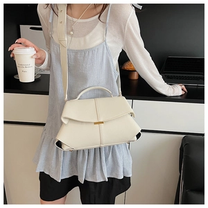 Detail of a creamy white pebbled leather handbag with top handle and wide shoulder strap
