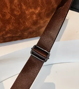 Detail of adjustable nylon shoulder strap with gunmetal buckle on brown tote bag