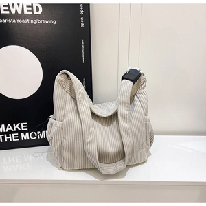 Detail of cream corduroy tote bag showing textured fabric and black adjustable buckle