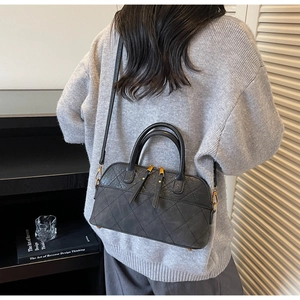 Detail of dark grey quilted shell bag with matte finish and gold-tone zippers