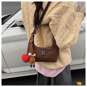 Détail d'un sac demi-lune en daim marron avec un charmant pompon décoratif